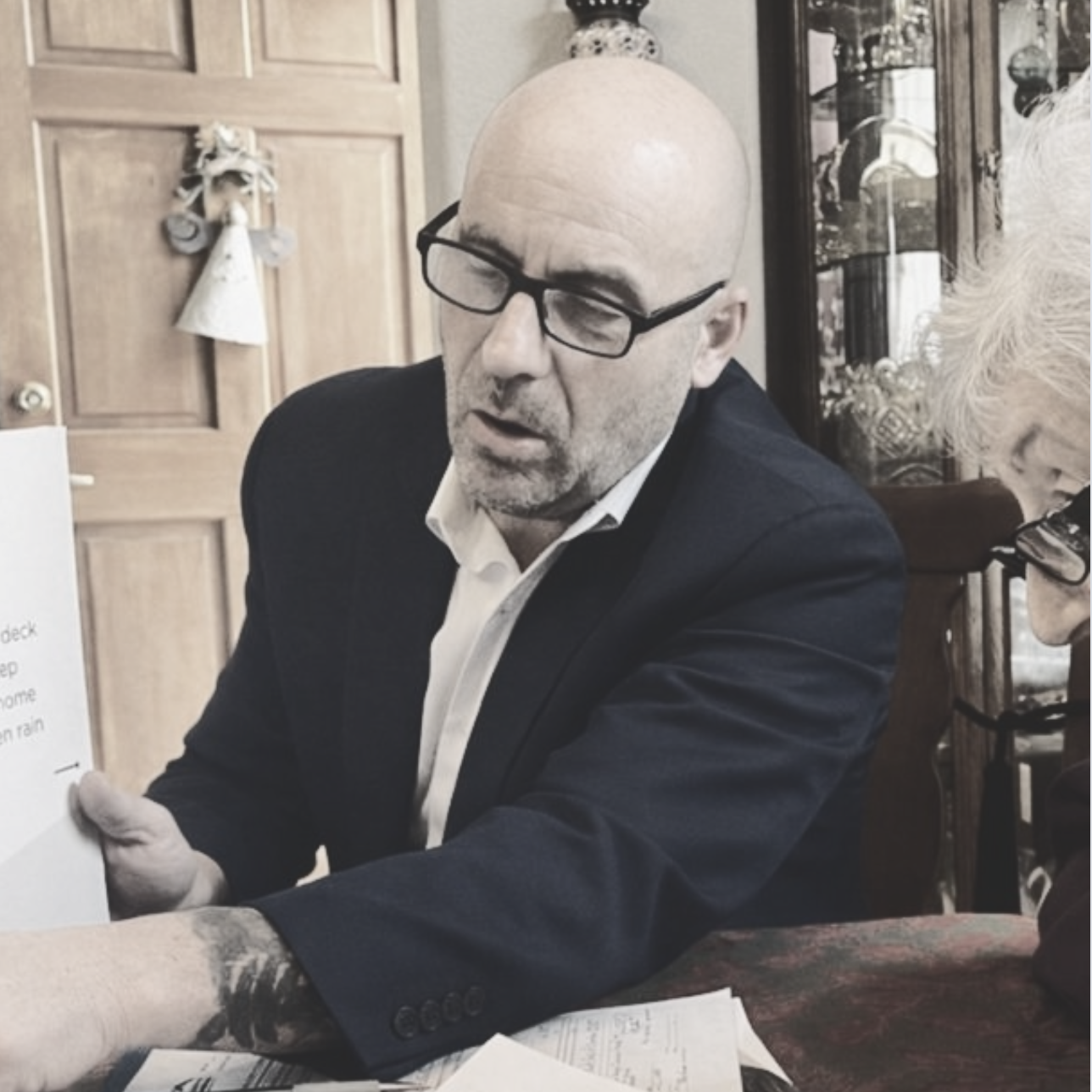 A man in glasses discusses insurance contract with client